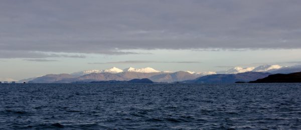 Cold, grey sea with a background of the Nevis range of mountains covered in snow