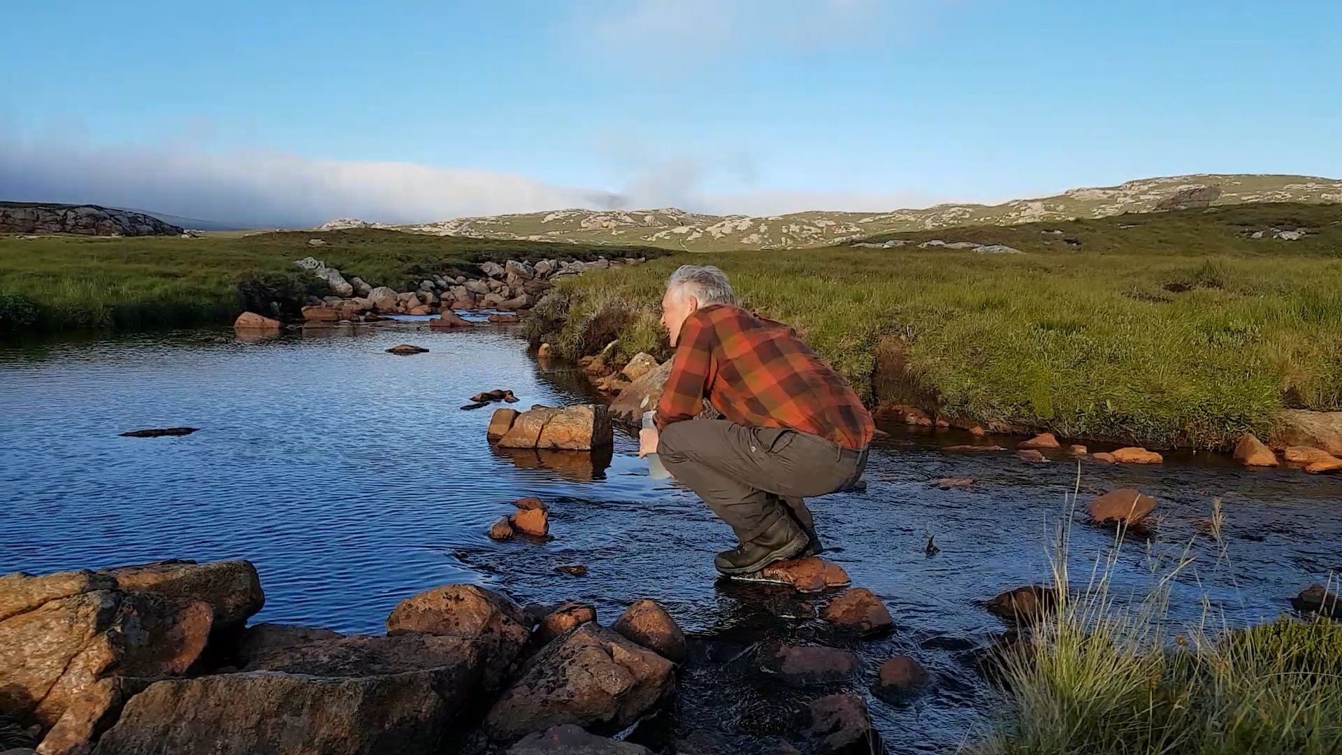 Collecting fresh water from the peaty burn at Strath Chailleach, near Cape Wrath, NW Scotland